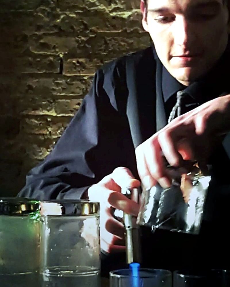 The owner of Chicago Beverage Experience torching a cocktail garnish behind the bar